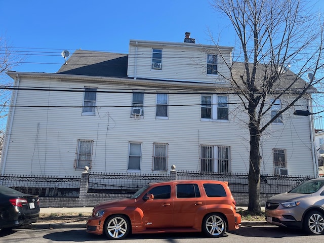 view of home's exterior with a chimney and fence