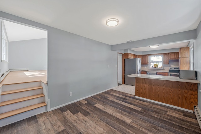 kitchen with wood finished floors, brown cabinetry, visible vents, a peninsula, and appliances with stainless steel finishes