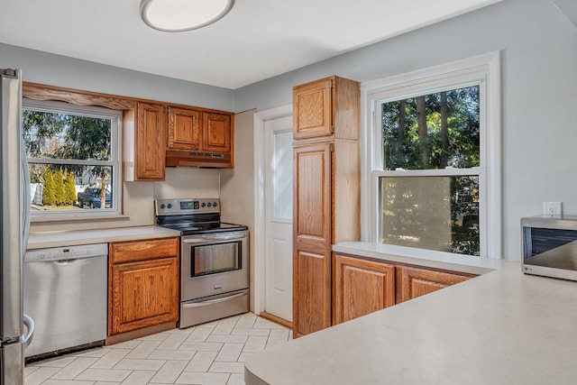 kitchen with under cabinet range hood, appliances with stainless steel finishes, a wealth of natural light, and light countertops