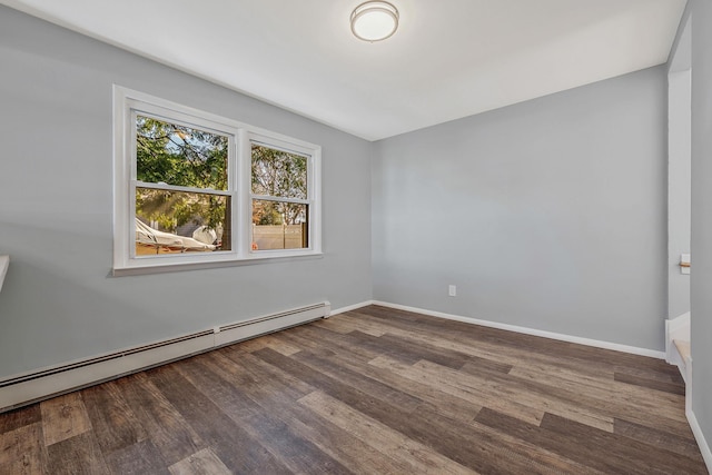 spare room featuring a baseboard heating unit, baseboards, and wood finished floors