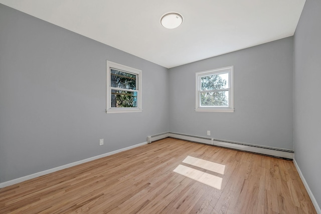 unfurnished room featuring wood finished floors, baseboards, and a baseboard radiator