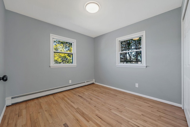 spare room with a baseboard radiator, baseboards, and light wood-style flooring