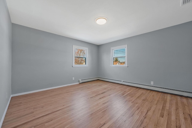 spare room featuring visible vents, baseboards, wood finished floors, and a baseboard heating unit