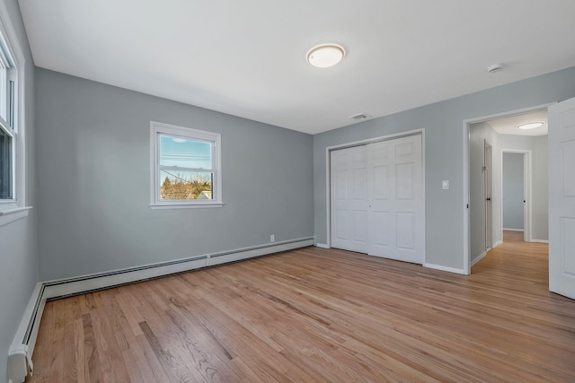 unfurnished bedroom featuring visible vents, baseboards, a closet, light wood-type flooring, and baseboard heating