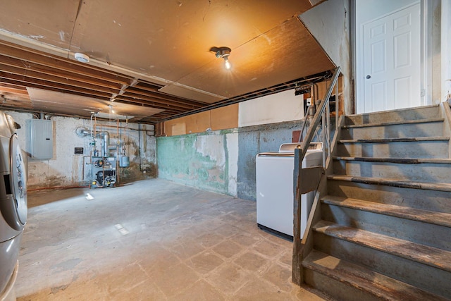 unfinished below grade area with electric panel, washer / dryer, a heating unit, and stairs