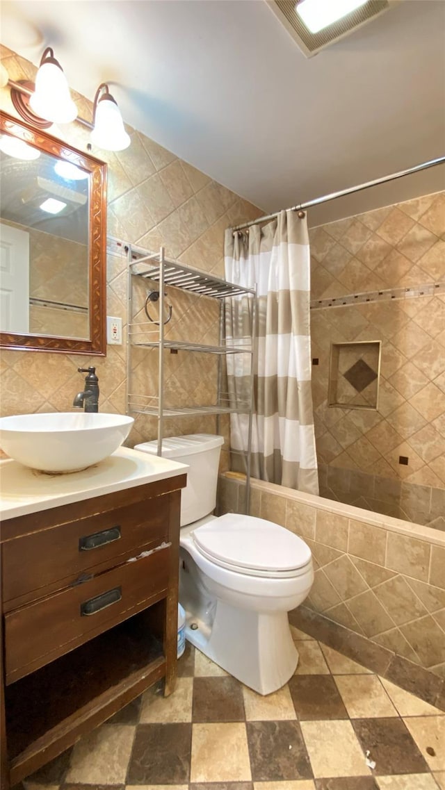 bathroom featuring visible vents, toilet, vanity, decorative backsplash, and tile walls