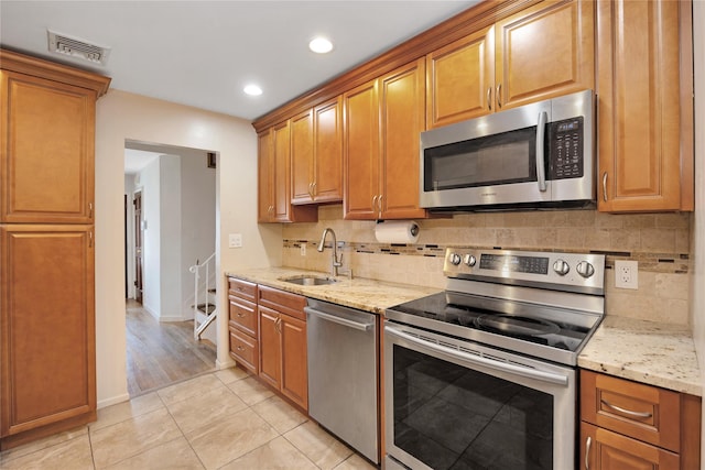 kitchen with light stone countertops, visible vents, a sink, appliances with stainless steel finishes, and backsplash