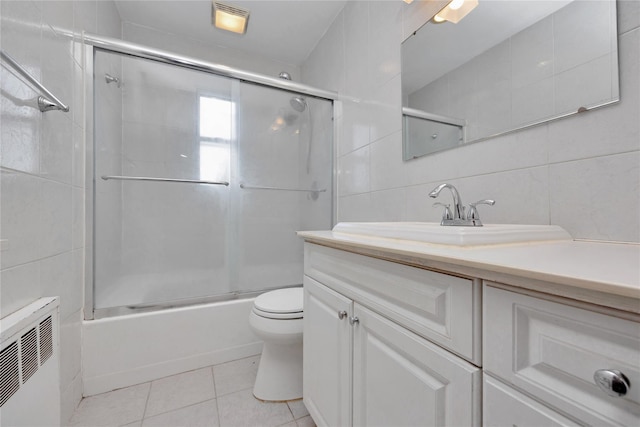 full bathroom featuring tile patterned flooring, tile walls, toilet, radiator heating unit, and vanity