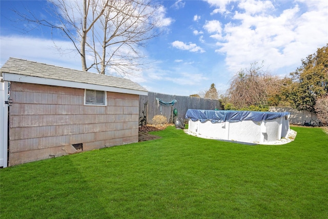 view of yard with an outbuilding, a fenced in pool, and fence