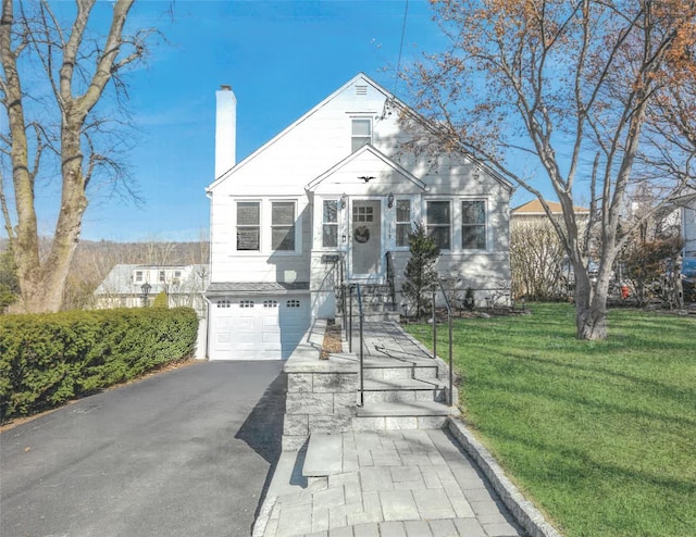 view of front of property featuring a chimney, a front lawn, a garage, and aphalt driveway