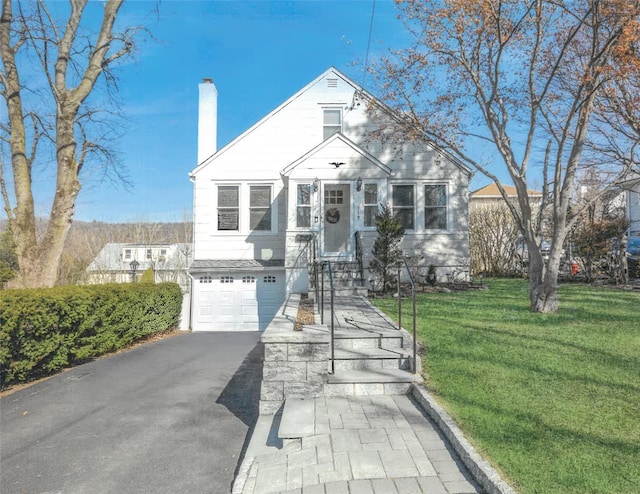 view of front of property with an attached garage, driveway, a chimney, and a front yard