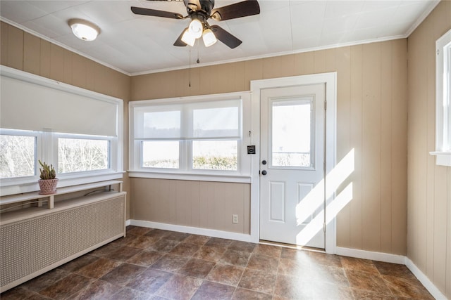 interior space with ornamental molding, stone finish flooring, radiator, baseboards, and ceiling fan