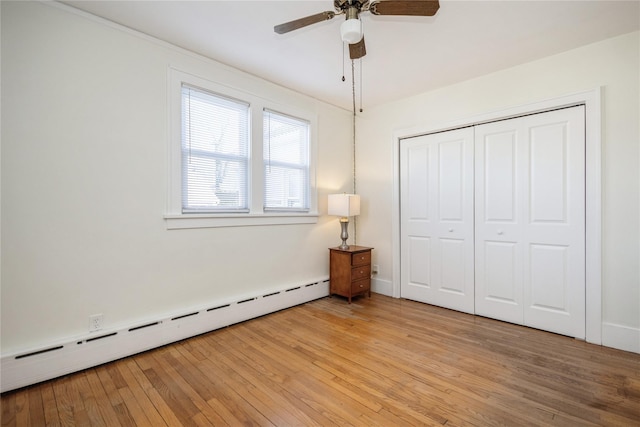 unfurnished bedroom with ceiling fan, light wood-style flooring, a closet, and a baseboard radiator