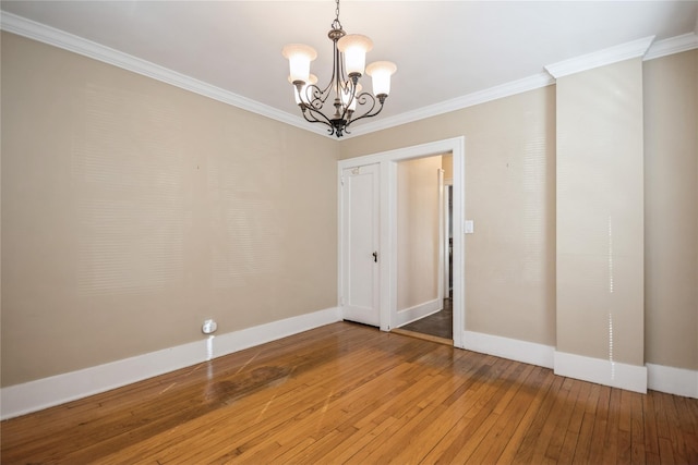 spare room featuring baseboards, wood-type flooring, a notable chandelier, and ornamental molding