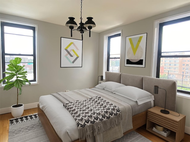 bedroom featuring multiple windows, an inviting chandelier, baseboards, and wood finished floors