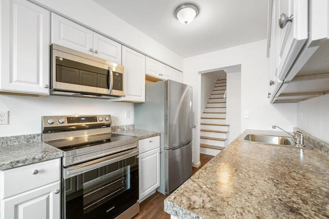 kitchen featuring dark wood-style floors, appliances with stainless steel finishes, white cabinetry, and a sink