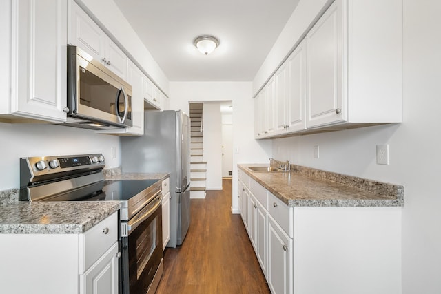 kitchen with a sink, dark wood finished floors, white cabinetry, appliances with stainless steel finishes, and light countertops