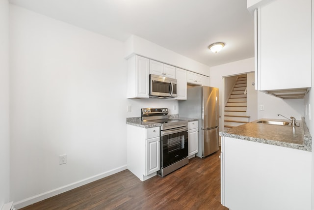 kitchen with baseboards, dark wood finished floors, appliances with stainless steel finishes, white cabinets, and a sink