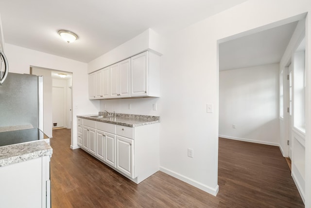 kitchen with a sink, dark wood finished floors, white cabinetry, freestanding refrigerator, and light countertops