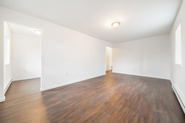 empty room featuring dark wood-type flooring, baseboards, and baseboard heating