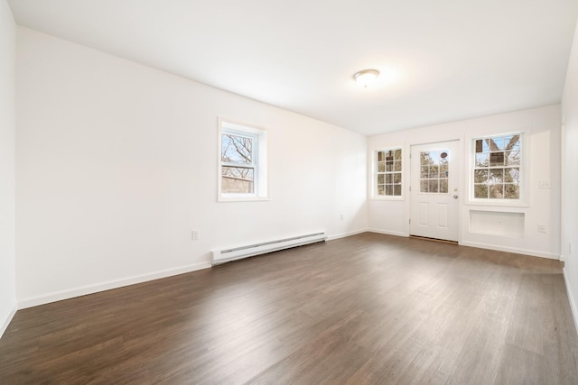 empty room featuring dark wood-style floors, a baseboard heating unit, and baseboards