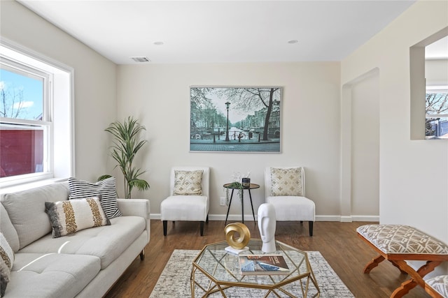 living room featuring visible vents, baseboards, and wood finished floors