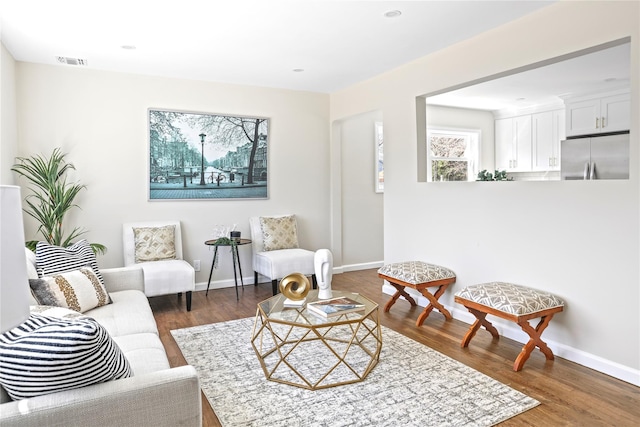 living area featuring visible vents, baseboards, and wood finished floors