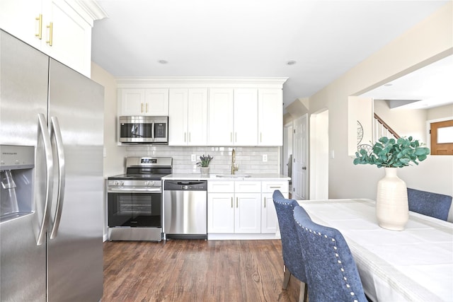 kitchen with a sink, backsplash, stainless steel appliances, light countertops, and dark wood-style flooring