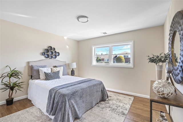 bedroom featuring visible vents, baseboards, and wood finished floors