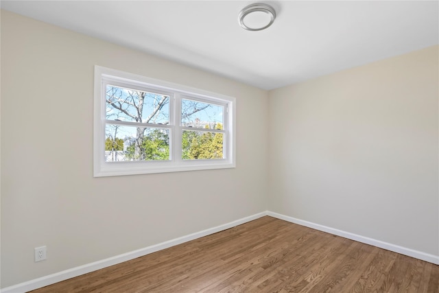 spare room featuring baseboards and wood finished floors