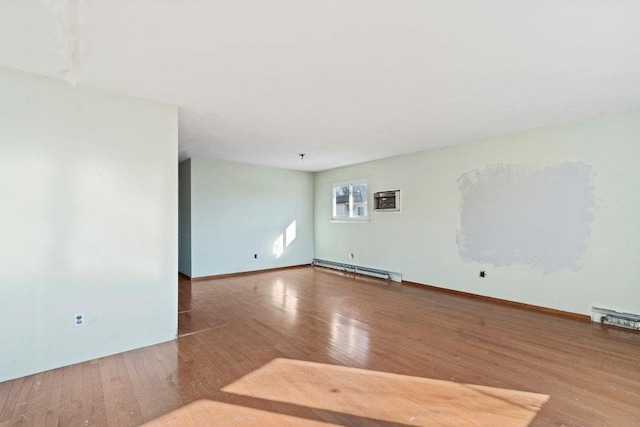 unfurnished room featuring a baseboard heating unit, baseboards, and hardwood / wood-style floors