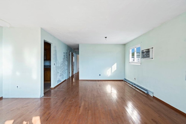 empty room featuring baseboard heating, a wall mounted AC, baseboards, and wood finished floors