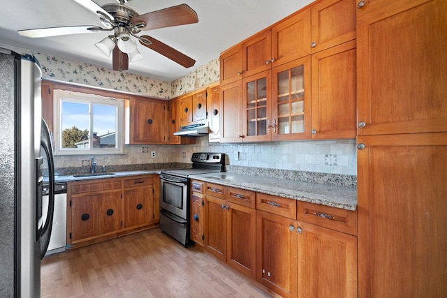 kitchen with brown cabinetry, under cabinet range hood, and stainless steel appliances