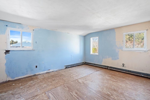 unfurnished room with a baseboard radiator and vaulted ceiling