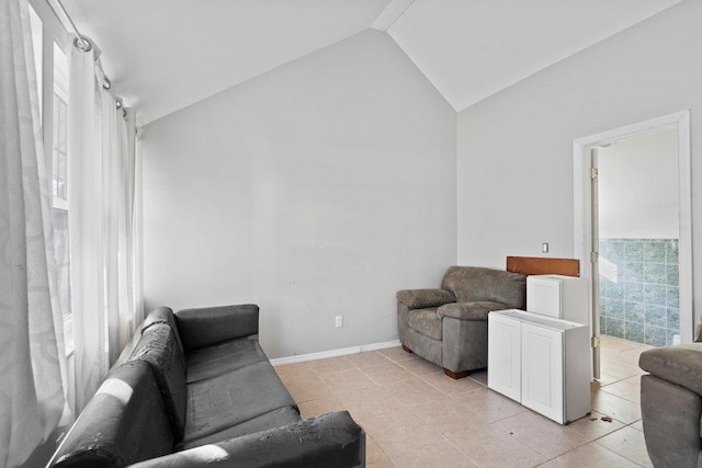 living area featuring light tile patterned floors, baseboards, and lofted ceiling