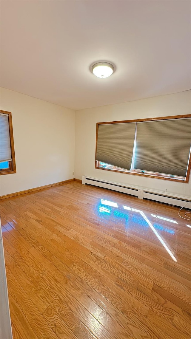 spare room featuring baseboards, baseboard heating, and wood finished floors