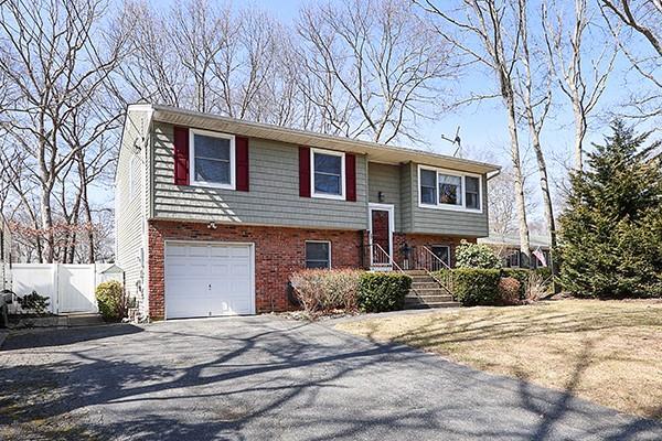 split foyer home featuring aphalt driveway, an attached garage, fence, and brick siding