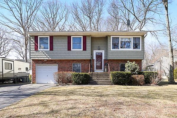 split foyer home featuring a garage, brick siding, a front lawn, and aphalt driveway