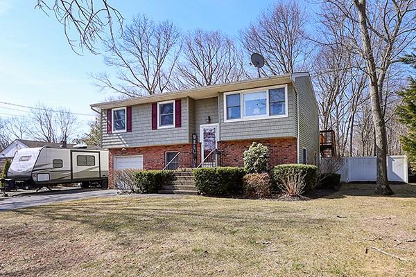 split foyer home with a front lawn, an attached garage, fence, and brick siding