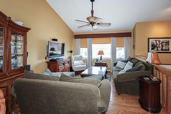 living area with a ceiling fan, lofted ceiling, and wood finished floors