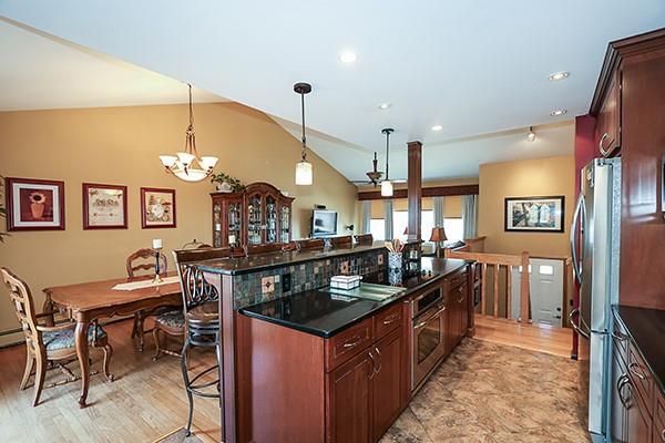 kitchen with a kitchen breakfast bar, a kitchen island, stainless steel appliances, vaulted ceiling, and hanging light fixtures