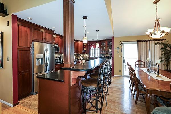 kitchen featuring dark countertops, a kitchen island, an inviting chandelier, stainless steel fridge, and ornate columns