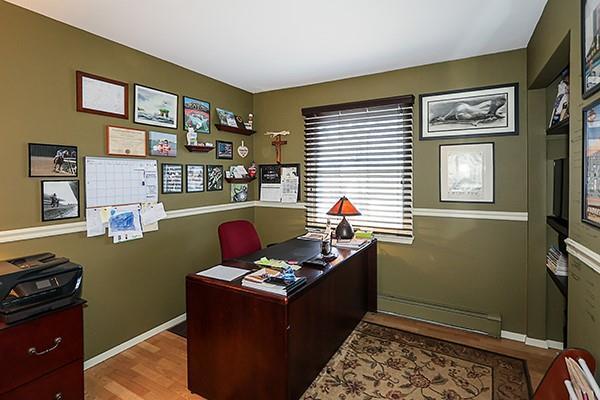 office space featuring a baseboard heating unit, baseboards, and wood finished floors