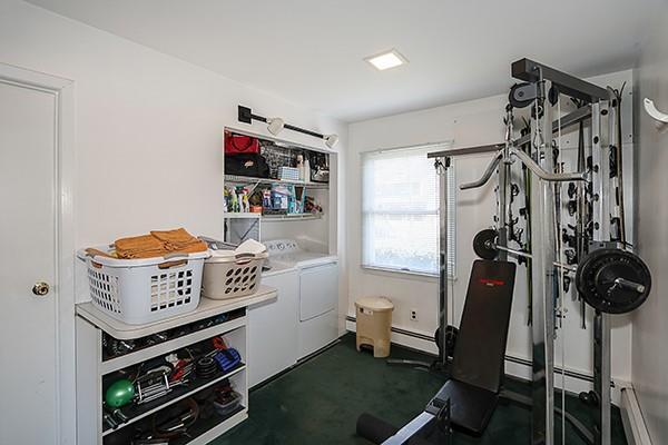 workout area with washer and dryer, dark colored carpet, and a baseboard radiator