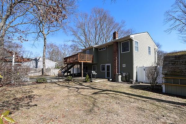 back of property featuring a chimney, a deck, stairs, and fence