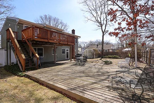 wooden deck with stairs, an outdoor structure, a fenced backyard, and a shed