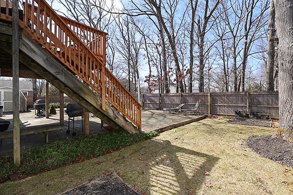 view of yard with a wooden deck, a patio area, stairs, and fence