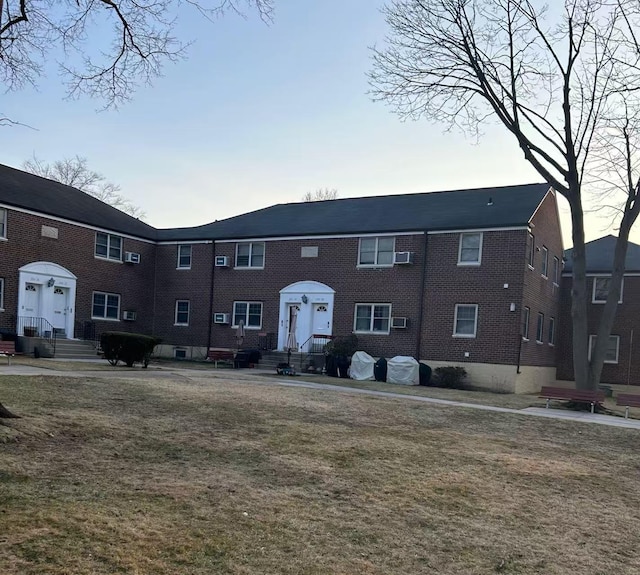 view of property featuring brick siding and a front lawn