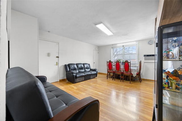 living room featuring baseboards, light wood-type flooring, and a wall mounted AC