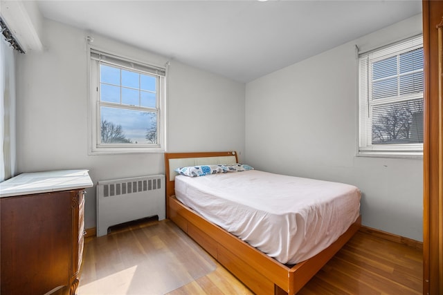 bedroom with radiator and wood finished floors